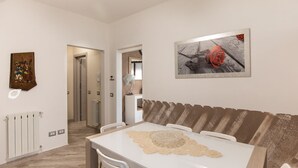 Un comedor con una mesa blanca, sillas con motivos florales y un mantel individual color beige.