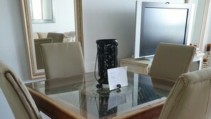 A dining area with a glass-top table, four upholstered chairs, a television, and a decorative black vase. - Luxury apartment in Los Alisios (Santa Cruz de Tenerife)
