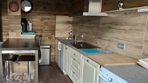 Una cocina moderna con paredes de madera, un lavamanos de acero inoxidable, armarios blancos y un lavavajillas empotrado.