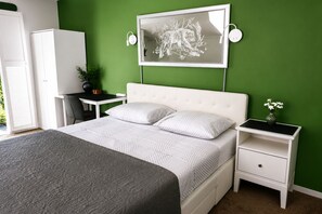 A bedroom with a bed, bedside tables, a desk, a chair, a wardrobe, and a wall-mounted artwork. - B&B Hotel Elselina (Schiedam)
