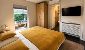 Une chambre à coucher avec un lit, un téléviseur, un radiateur et une vue sur l’extérieur.