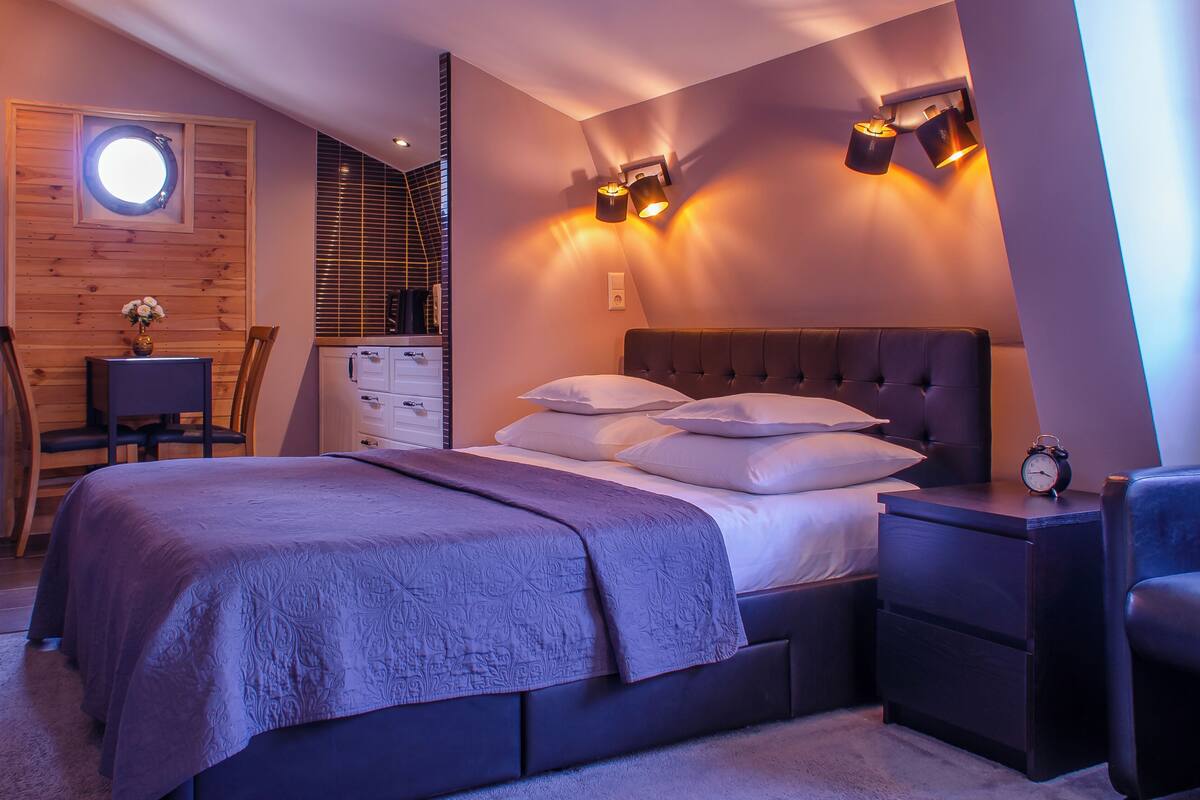 A modern bedroom with a large bed, bedside tables, a desk, and a chair.