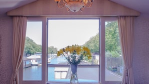 Una habitación con un ventanal grande, una araña y una mesa con un jarrón de flores.