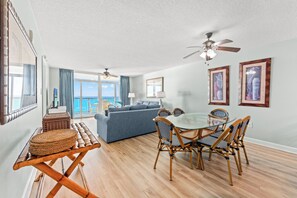 A room with a dining table, chairs, a sofa, and a ceiling fan. - Clean Oceanfront Condo, Free Wifi, Lazy River | Crescent Keyes - 1208 (North Myrtle Beach)