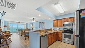 A spacious kitchen with wooden cabinets, stainless steel appliances, and a large island. - Clean Oceanfront Condo, Free Wifi, Lazy River | Crescent Keyes - 1208 (North Myrtle Beach)