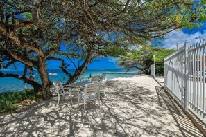 A beachside seating area with a view of the sea and a white fence. - Beachfront Two-Bedroom Villa (Savaneta)