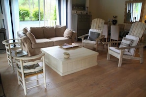 A living room with a beige sofa, white armchairs, a white coffee table, and a wooden floor. - Comfortable house with pool G0269 (Lacanau)