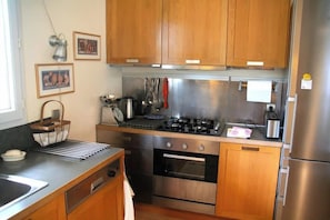 A kitchen with wooden cabinets, a stainless steel refrigerator, and a gas stove. - Comfortable house with pool G0269 (Lacanau)