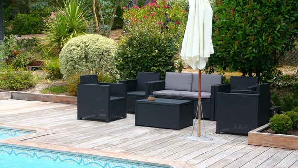 A poolside area with a wooden deck, black wicker furniture, and a white umbrella. - Comfortable house, big pool with wooden terrace, ideal location (Lacanau)