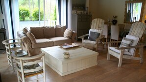 A living room with a beige sofa, white armchairs, a white coffee table, and a wooden cabinet. - Comfortable house, big pool with wooden terrace, ideal location (Lacanau)