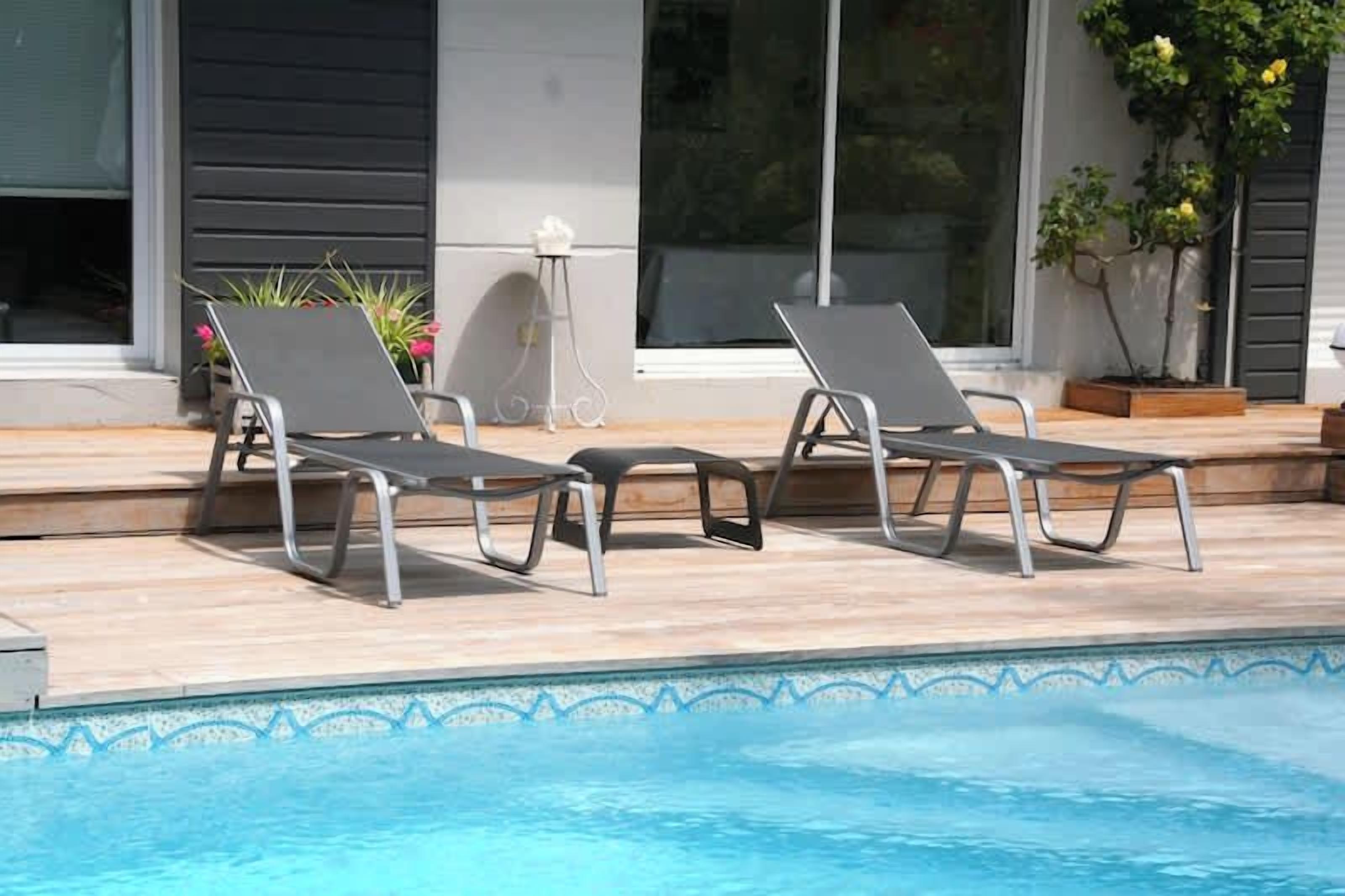 Une piscine avec deux chaises longues et une petite table.