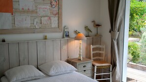 A bedroom with a bed, pillows, a nightstand with a lamp, a chair, and a wall decorated with children's drawings. - Comfortable house, big pool with wooden terrace, ideal location (Lacanau)