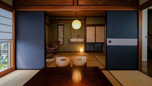 Een traditionele Japanse kamer met tatami vloerbedekking, een lage tafel, schuifdeuren en een hanglamp.
