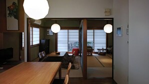 Een traditioneel Japans interieur met tatami vloeren, een houten eettafel en schuifdeuren met uitzicht.