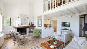 A spacious living room with a fireplace, a dining area, and a balcony with white railings. - Spectacular Views, Pool & 5-Bedroom Family-Friendly Holiday Home in Provence (Fayence)