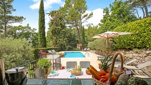 A poolside dining area with a table set for two, a wicker basket with fruits and vegetables, and a stone wall in the background. - Spectacular Views, Pool & 5-Bedroom Family-Friendly Holiday Home in Provence (Fayence)