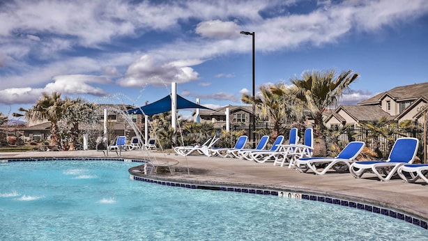 A swimming pool with blue lounge chairs and a blue canopy.