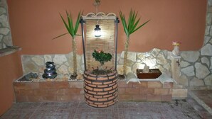 A stone wall with a brick planter containing a small tree and two potted plants. - Apartment/ flat - SICULIANA House with garden (SICULIANA)