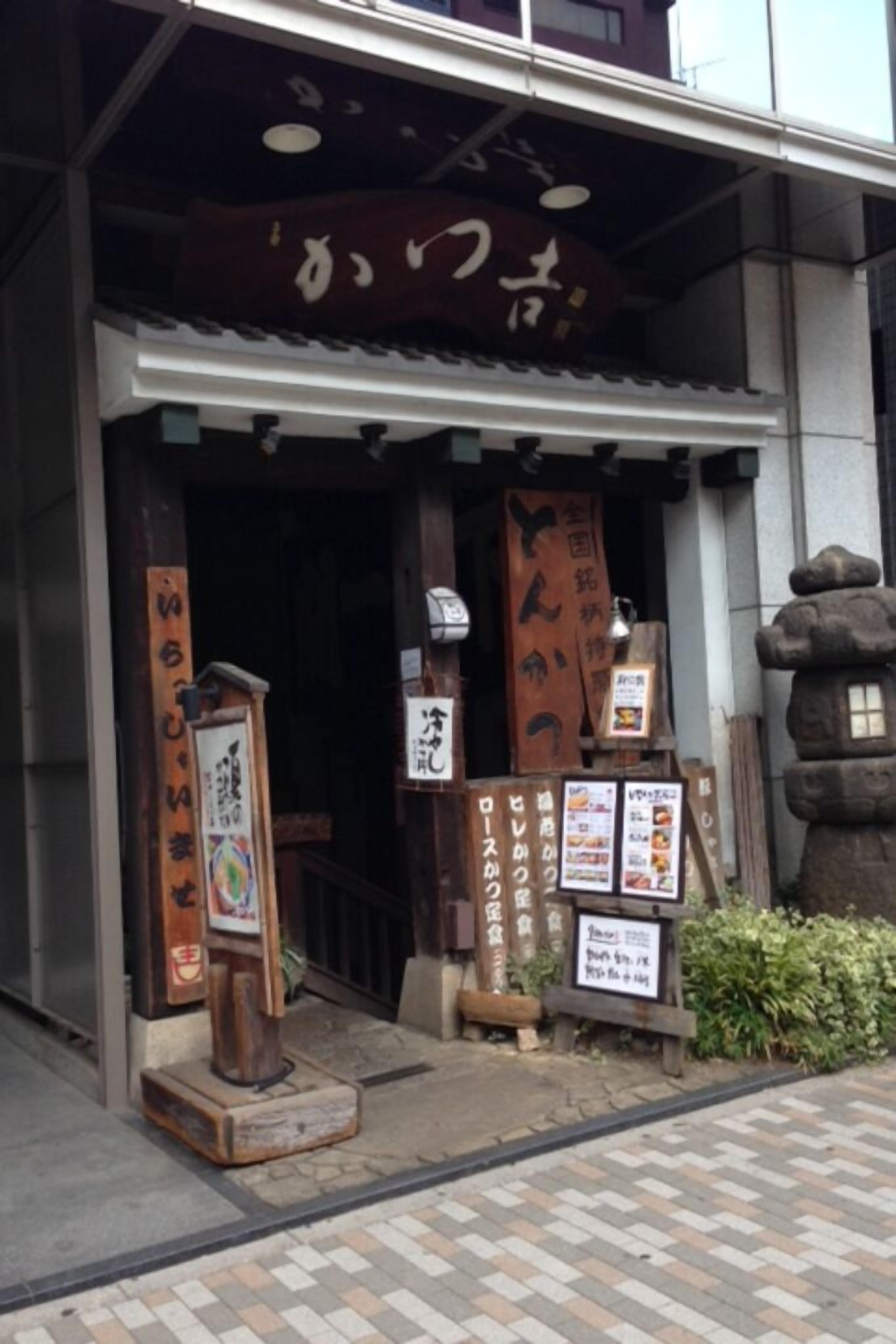 A traditional Japanese entrance with wooden signage and a stone lantern.