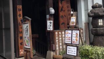 A traditional Japanese entrance with wooden signage and a stone lantern.