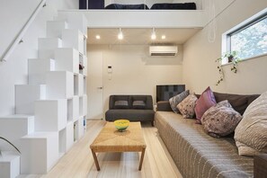 A modern living room with a staircase, a sofa, a coffee table, and a television.
