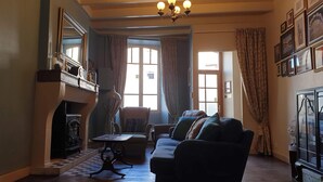 A traditional living room with a fireplace, a sofa, a table, and a chandelier. - A relaxed,  comfortable and cosy home (Chef Boutonne)