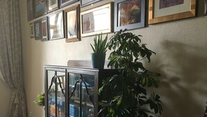 A room with a wooden floor, a glass cabinet with plants, a guitar, and framed pictures on the wall. - A relaxed,  comfortable and cosy home (Chef Boutonne)