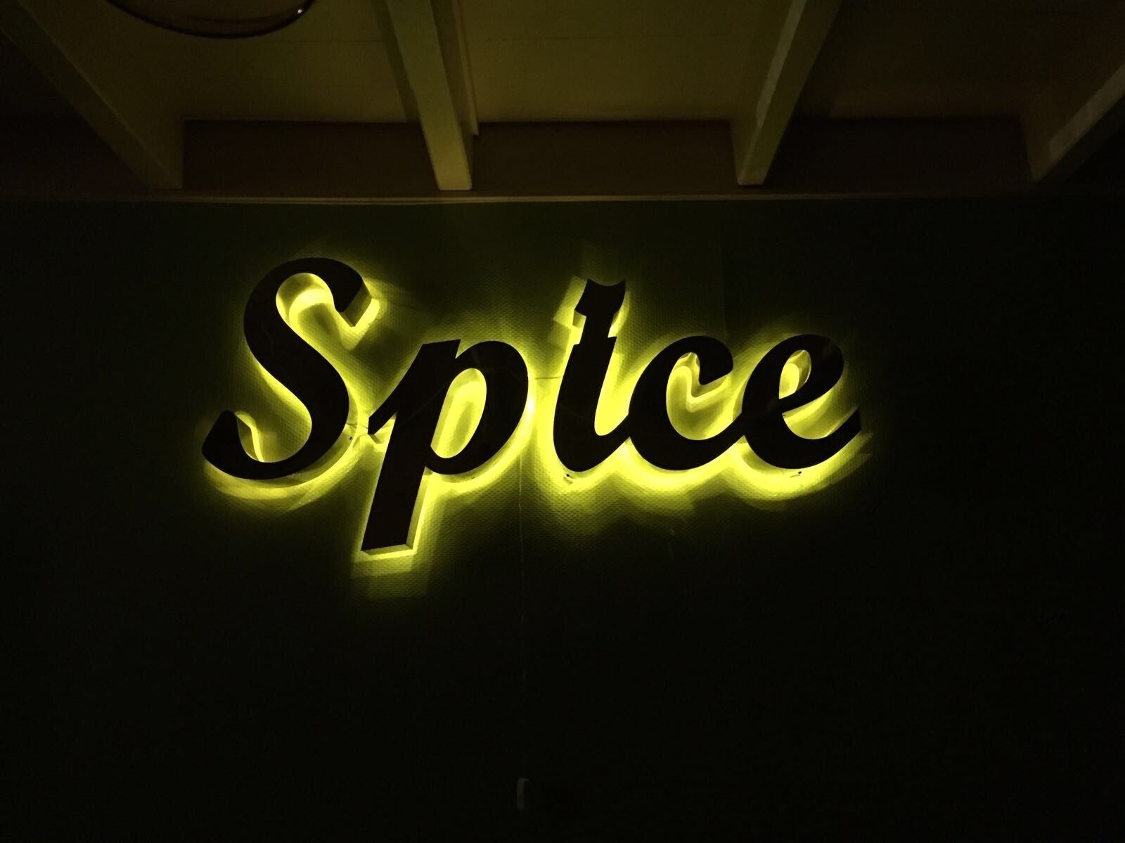 Ein Schild mit der leuchtenden Aufschrift 'Spice' in Gelb.