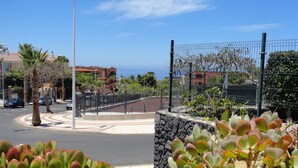 A coastal road with a stone wall and a metal fence.