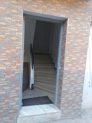 A staircase with a stone wall on either side, leading to an upper floor.