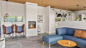 Un salon moderne avec un canapé bleu, deux fauteuils en cuir, une table basse en bois et une cheminée.