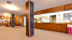 Ein Empfangsbereich mit einem Holzbüro, einer Uhr und einer Sitzecke mit roten Stühlen.