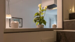 Une salle de bain avec un miroir, une plante en pot et un petit objet décoratif blanc posé sur le rebord de la fenêtre.