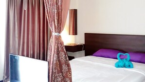 Een hotelkamer met een bed, een televisie, een lamp en een gordijn.