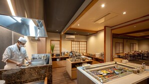 Un restaurante con un chef preparando comida, un bufé con diversos platos y decoración tradicional japonesa.