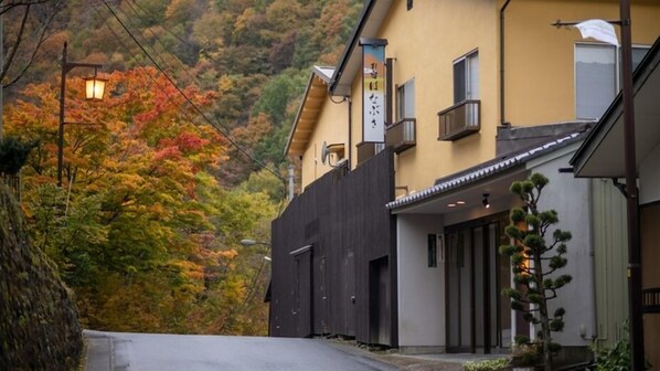 Il s'agit d'un bâtiment japonais traditionnel, avec une façade en bois, une entrée couverte et une enseigne.