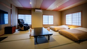 Una habitación japonesa tradicional con suelo de tatami, una mesa baja, un sofá y una cama.