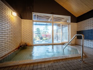 Un bain dans une source thermale, avec vue sur les arbres et un plafond en bois.