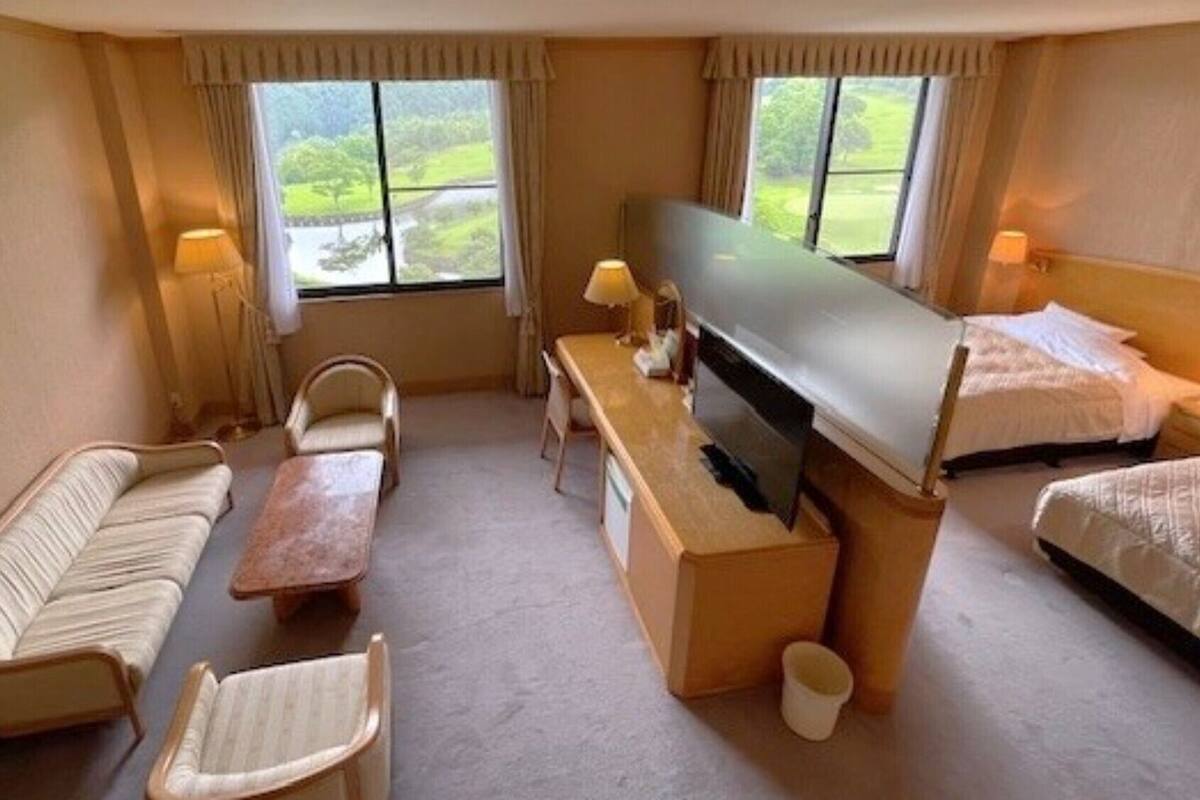 A hotel room with a sofa, a small table, a TV, and a bed.