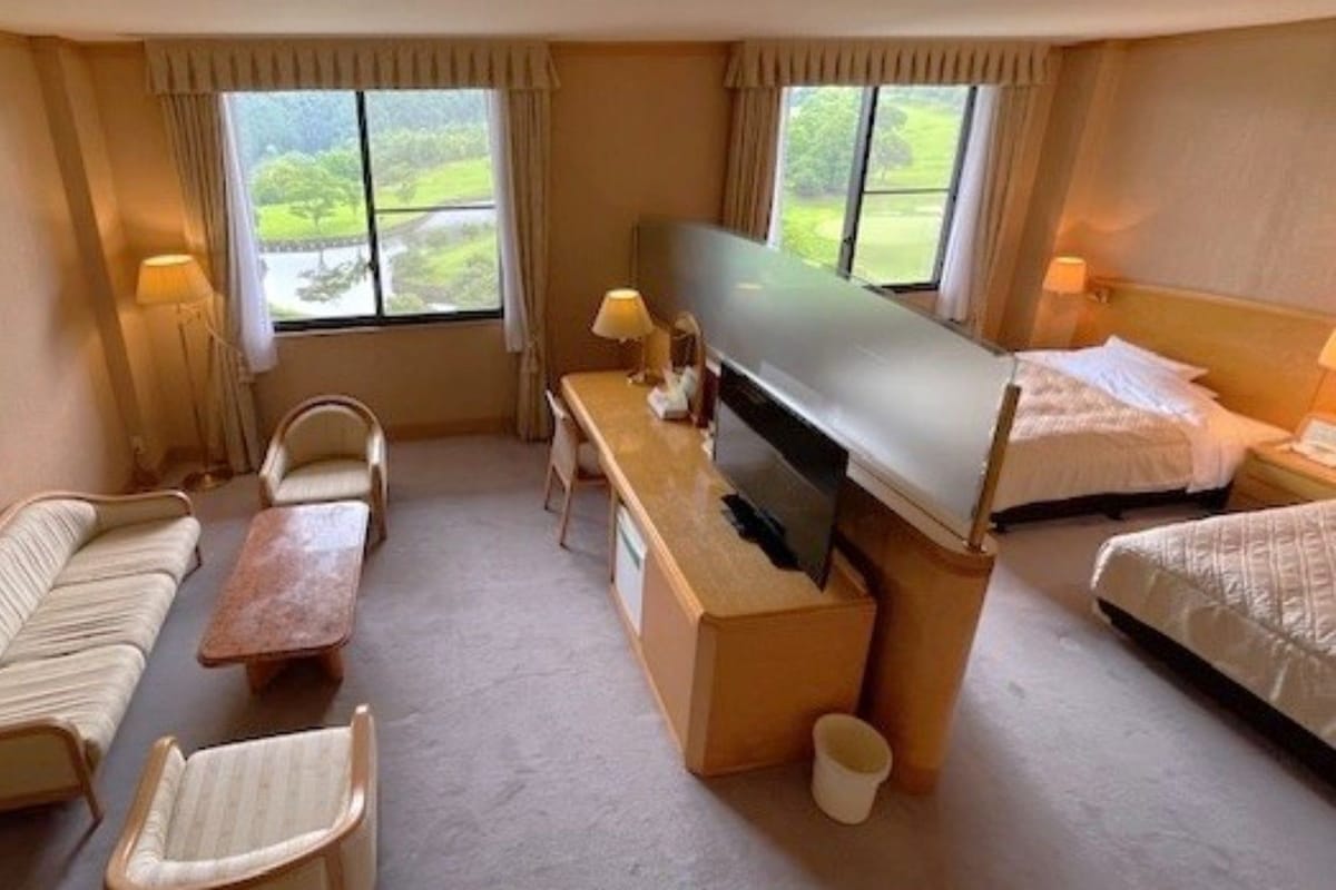 Una habitación de hotel con sofá, una mesita, televisor y cama.