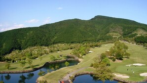 Un parcours de golf agrémenté de bassins, d’arbres et offrant une vue sur les montagnes en arrière-plan.