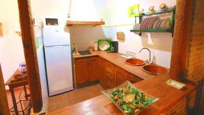 A kitchen with wooden cabinets, a refrigerator, a sink, and a dish rack.