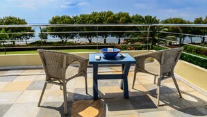 Ein Balkon mit zwei Korbstühlen, einem Tisch und einer Schale.