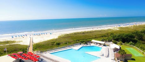 Un resort con una piscina grande, acceso a la playa y vistas al océano.