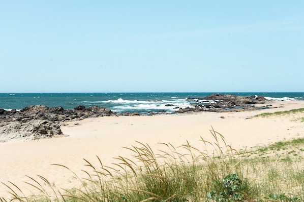 Enjoy the serene ocean views and stroll along the sandy beach with rocky outcrops.