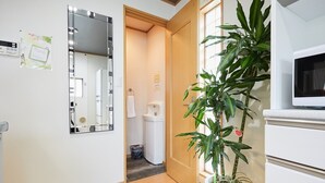 A hotel room with a wooden floor, a large mirror, a potted plant, a white sink, and a television. - 4min Shin-Okubo Sta&Very bright!/Free Wi (Shinjuku-ku)
