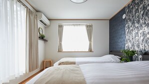 A hotel room with two beds, a window with curtains, an air conditioning unit, a clock, a small stool, and a plant. - 4min Shin-Okubo Sta&Very bright!/Free Wi (Shinjuku-ku)