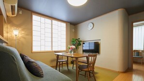 A cozy living room with a sofa, a dining table with chairs, a TV mounted on the wall, and a large window providing natural light. - 4min Shin-Okubo Sta&Very bright!/Free Wi (Shinjuku-ku)