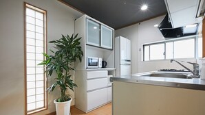 A modern kitchen with white cabinets, a microwave, a refrigerator, a sink, and a potted plant. - 4min Shin-Okubo Sta&Very bright!/Free Wi (Shinjuku-ku)