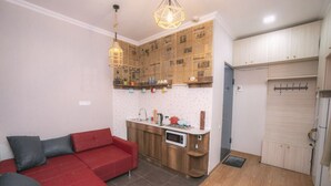 A compact living space with a red sofa, kitchenette, and wooden cabinets. - The Librarians' Flat (Dzveli Tbilisi)